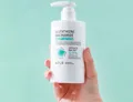 Body lotion pump bottle held in hand